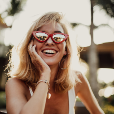 blonde woman in sunglasses smiling at camera outdoors
