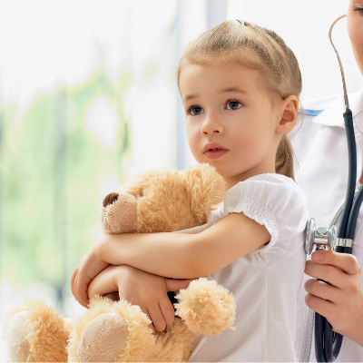 little girl holding a teddy bear while getting a checkup by doctor