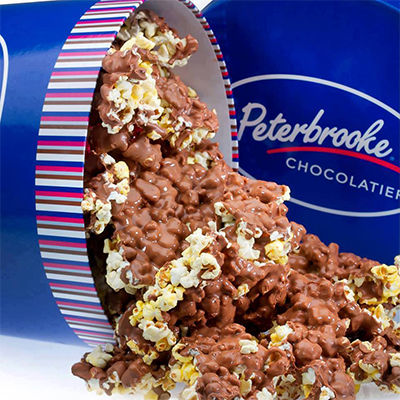 an opened box of chocolate over popcorns