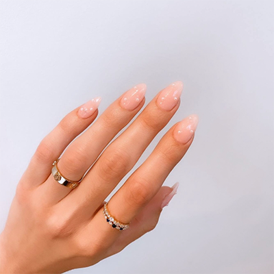 hand with oval nails and rings on index and ring fingers