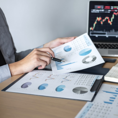 businessman at desk holding a paper of analytical charts and graph