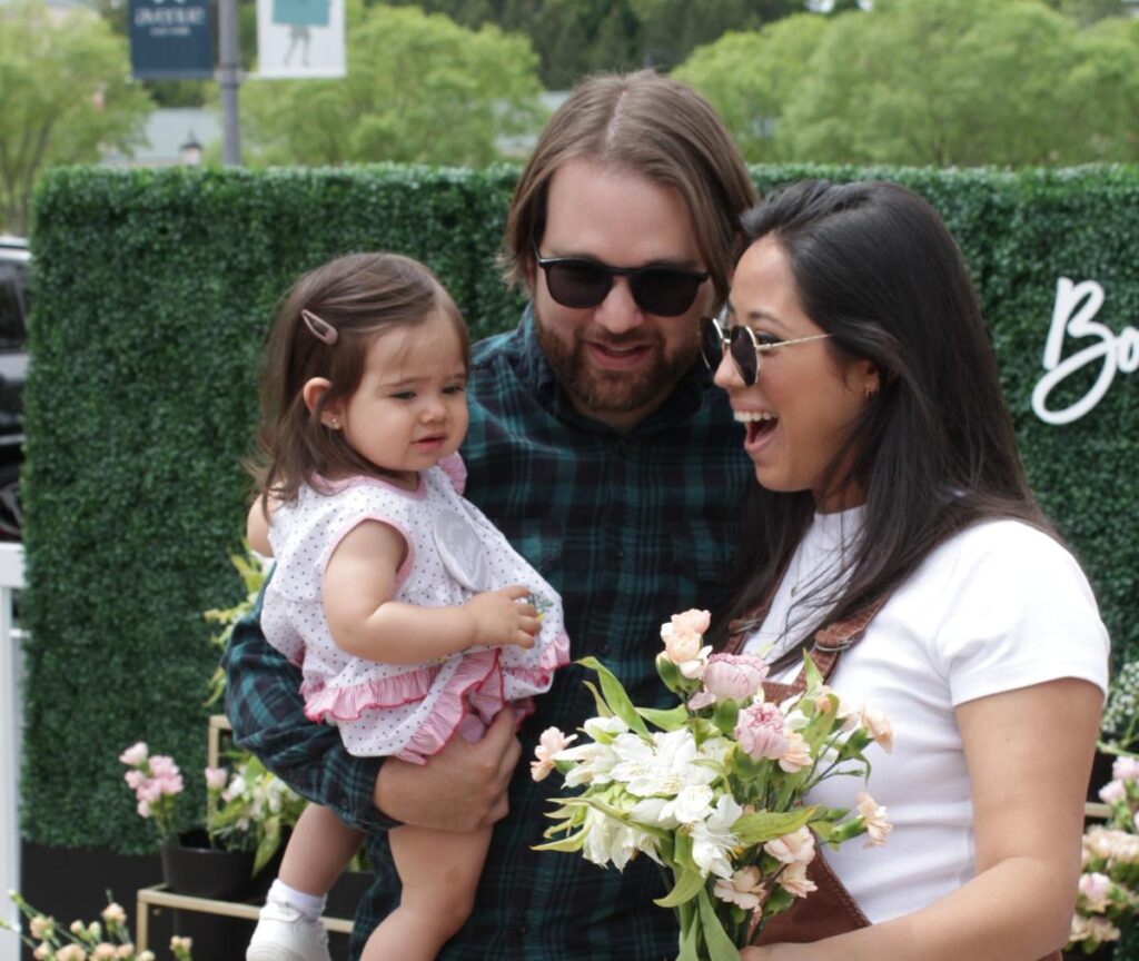 woman in sunglasses interacting with man holding a baby girl