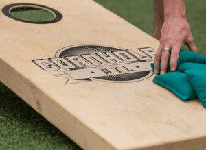 hand picking up bean bags placed on top of a cornhole board